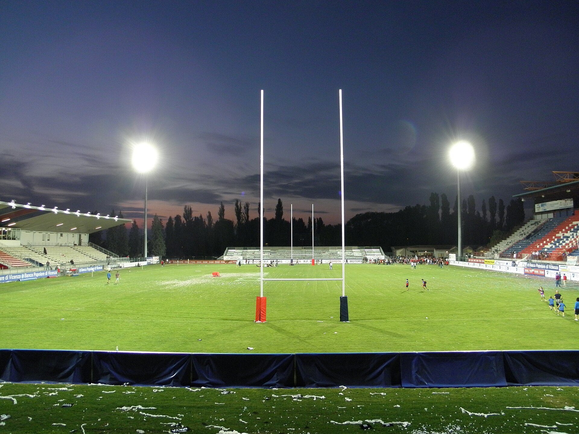Lo stadio Mario Battaglini di Rovigo al tramonto con i riflettori accesi e i pali da rugby